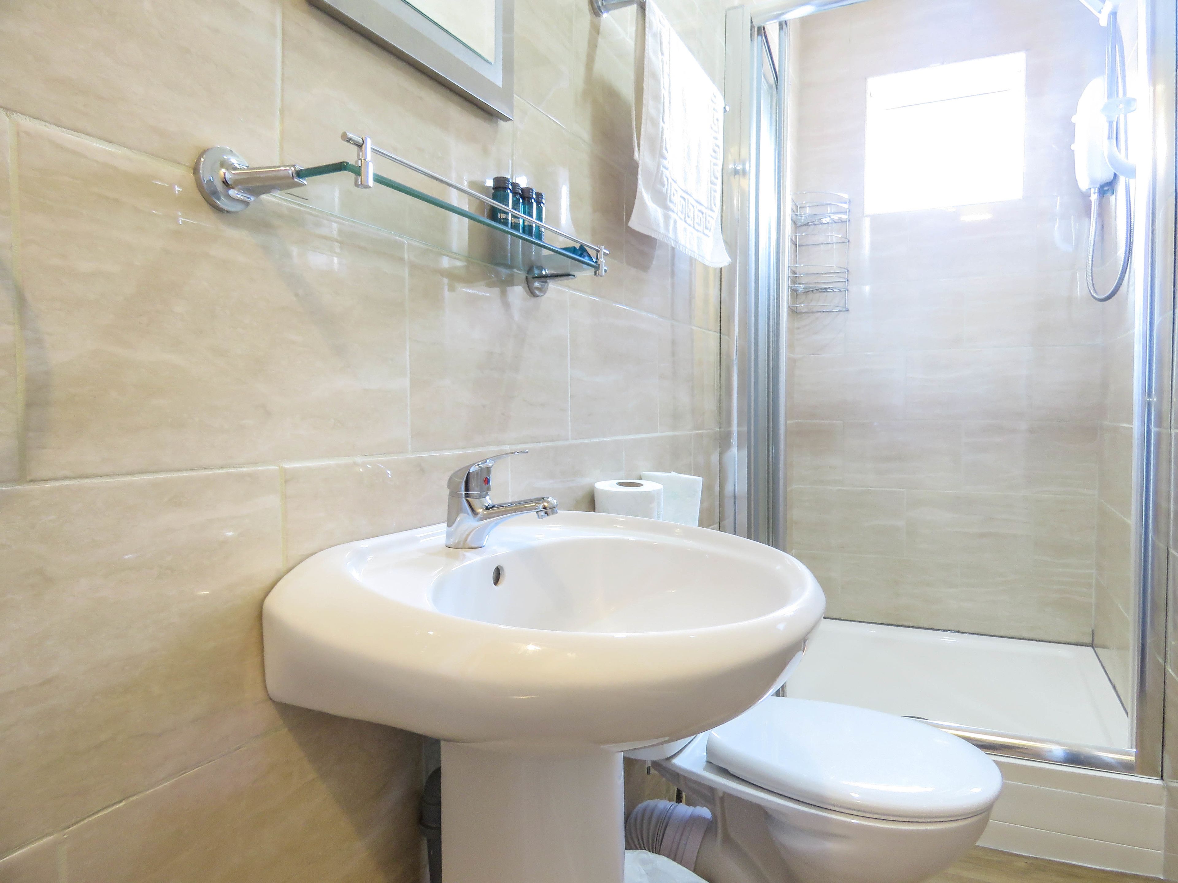 Ein Badezimmer mit Waschbecken, Toilette und einer Duschkabine aus Glas.