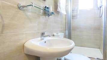 Ein Badezimmer mit Waschbecken, Toilette und einer Duschkabine aus Glas.
