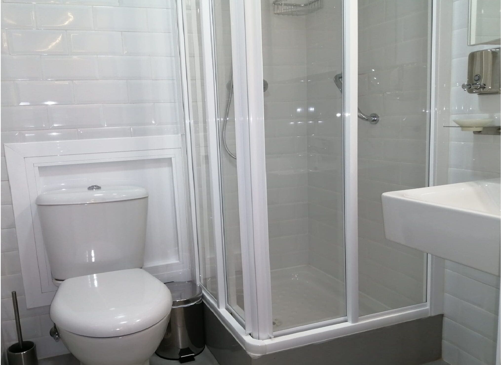 A modern bathroom with a toilet, a glass-enclosed shower, and a sink.