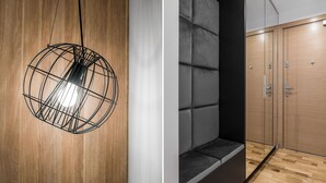 A modern interior with a spherical light fixture, a cushioned bench, and a wooden wardrobe.