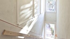 Un escalier avec une rampe en bois et une vue sur l’extérieur par une fenêtre.