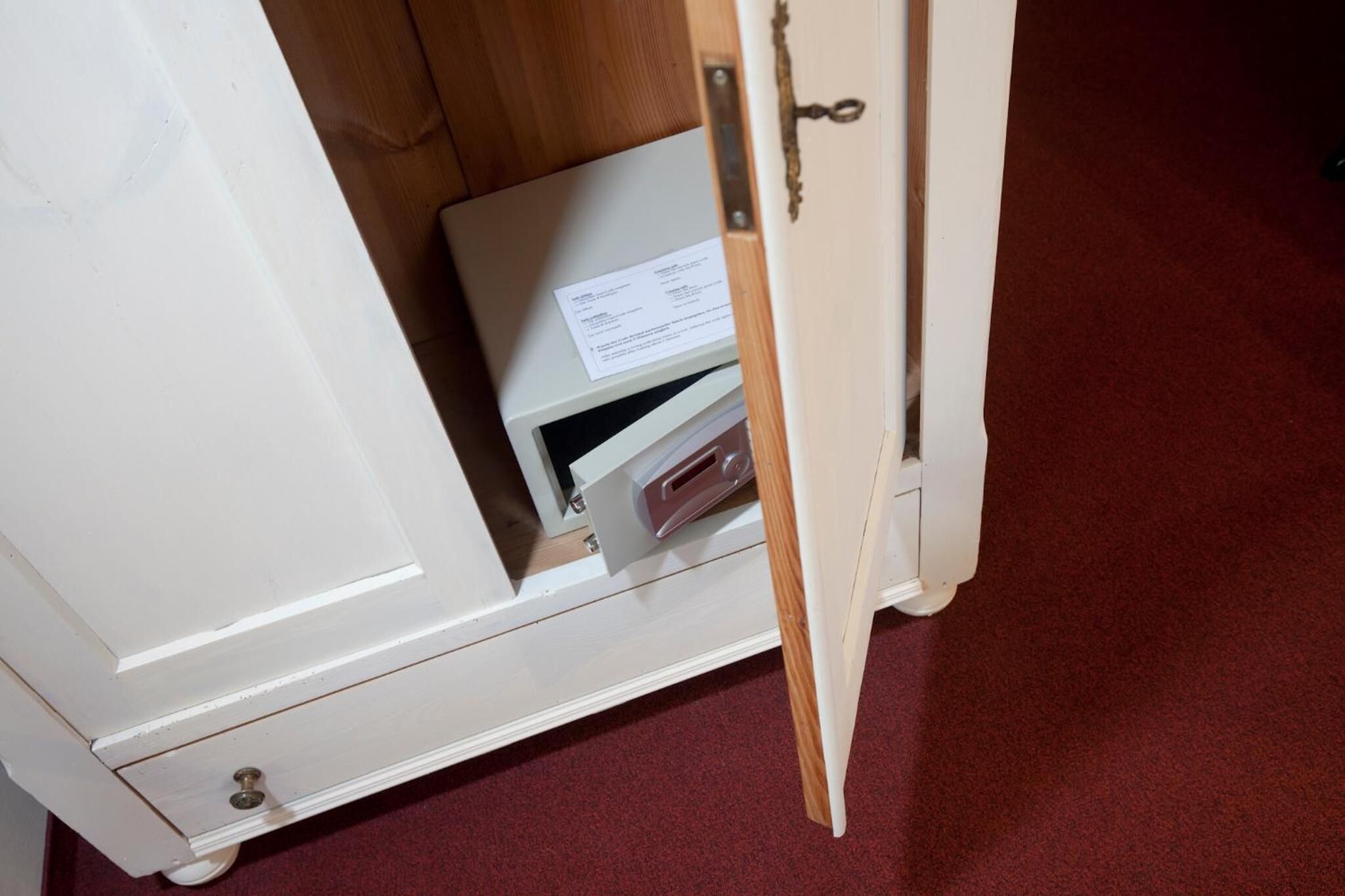 A white cabinet with a drawer containing a white box and a small electronic device.