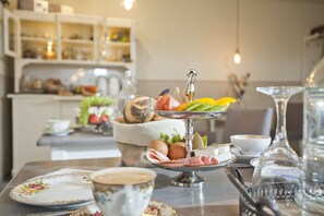 Una preparación para el desayuno con un plato de varios niveles, una taza de café y un jarrón decorativo.