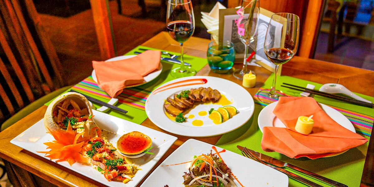 Una mesa de comedor con platos de comida, copas de vino y una carta.