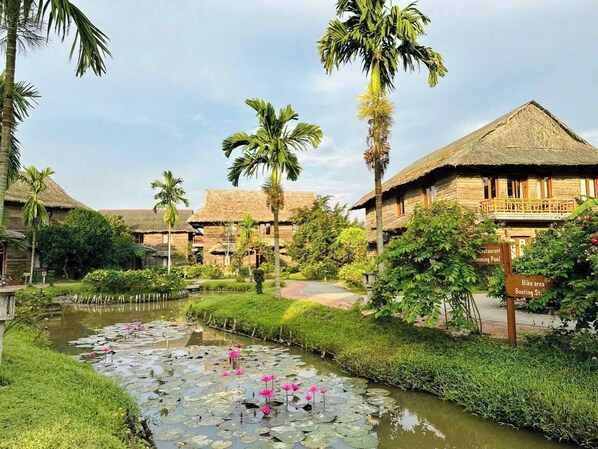 Un resort con edificios de techo de paja, una piscina y una zona para bicicletas.