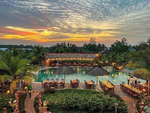 Un complejo turístico con piscina, zona de comedor al aire libre y bar.