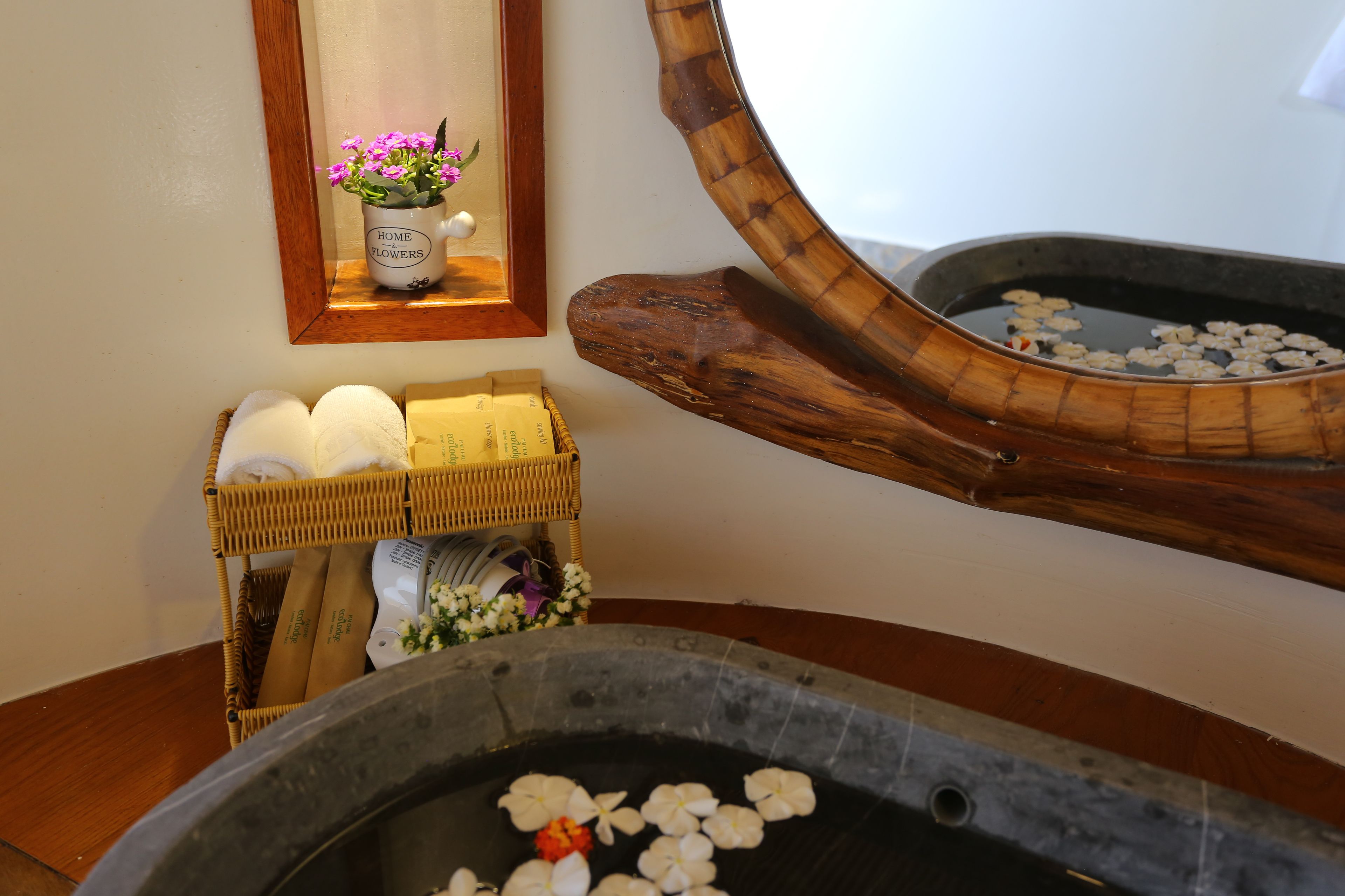 A bathroom with a wooden basin, a mirror, and a shelf with toiletries.
