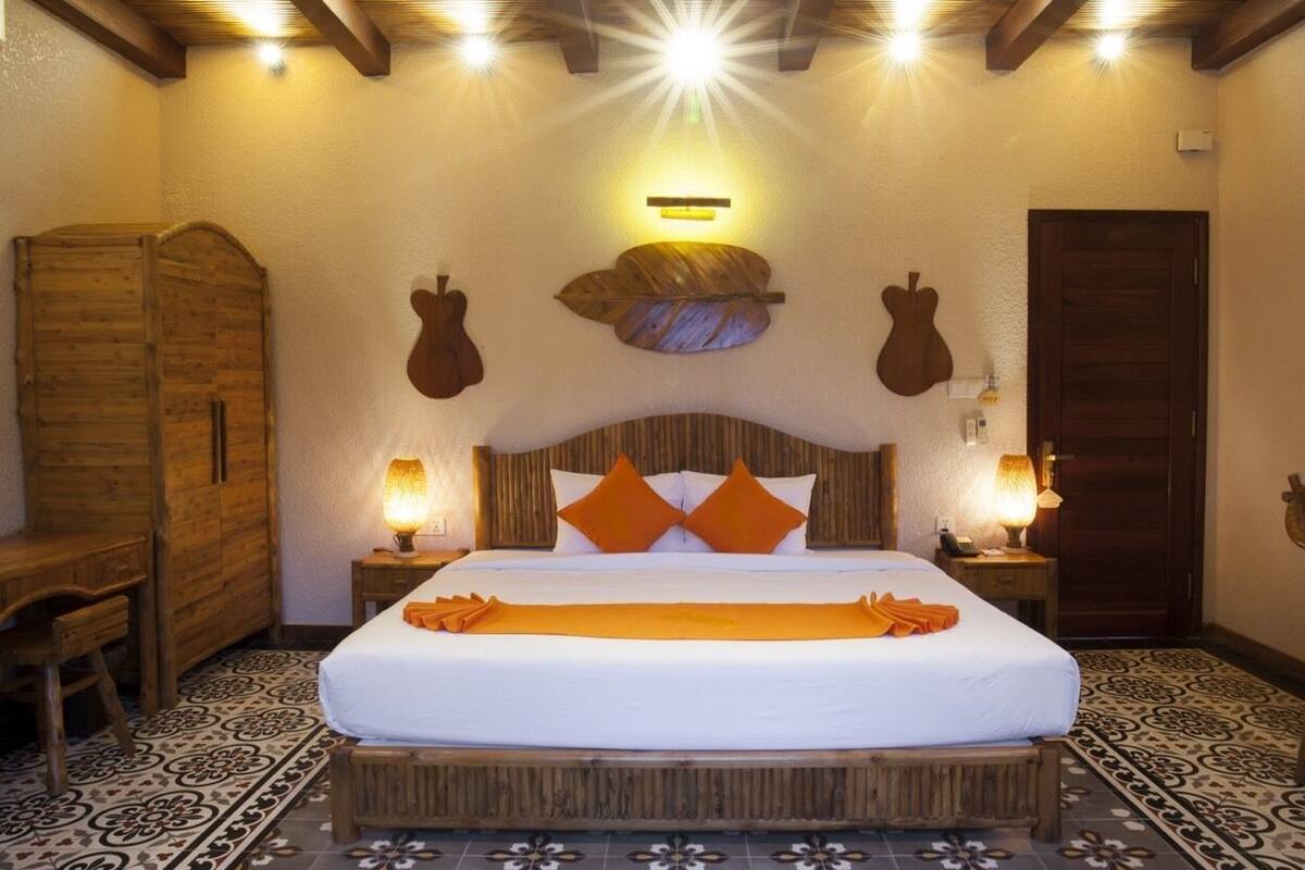 Une chambre à coucher bien rangée, avec un grand lit, une tête de lit en bois et deux lampes de chevet.