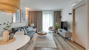 A modern living room with a sofa, coffee table, TV, and a dining area with a table and chairs. - Angielska Grobla City Center & Parking by Downtown Apartments (Gdansk)