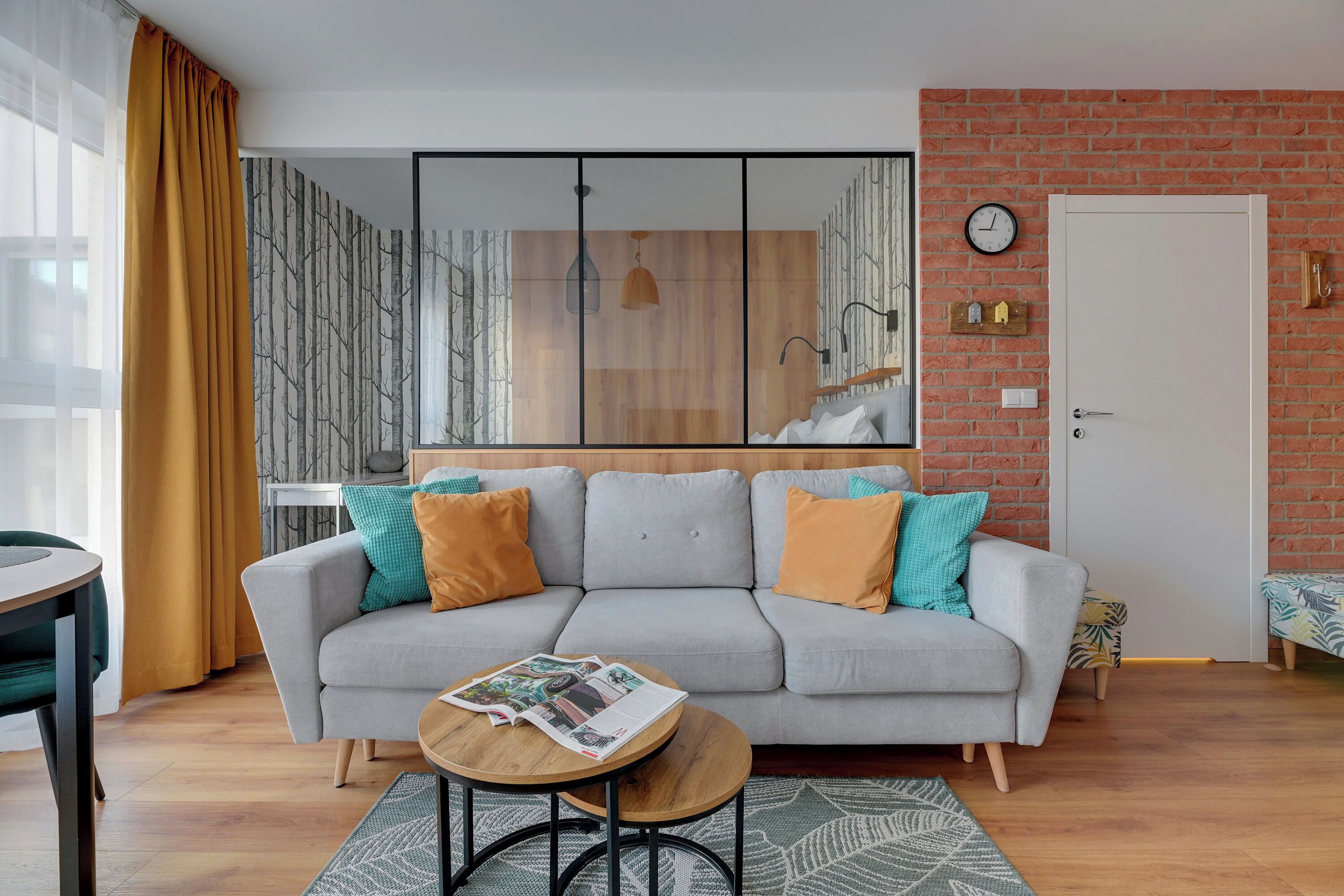 A modern living room with a grey sofa, wooden coffee table, and patterned rug.