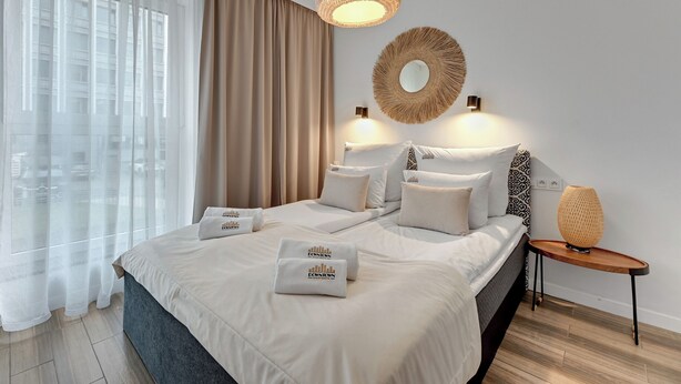 A hotel room with a large bed, a round mirror, and a bedside table with a lamp. - Angielska Grobla City Center & Parking by Downtown Apartments (Gdansk)