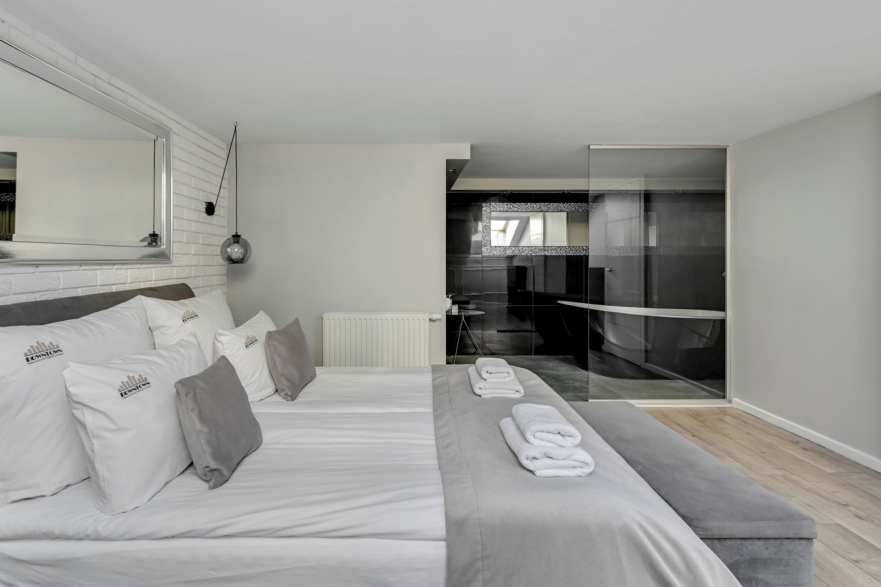 Ein modernes Schlafzimmer mit einem großen Bett, einer Bank und einer Dusche mit Glaswand.