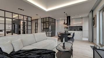 A modern living room with a sofa, a coffee table, and a dining area with chairs.