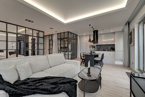 En moderne stue med sofa, sofabord og et spiseområde med stole.