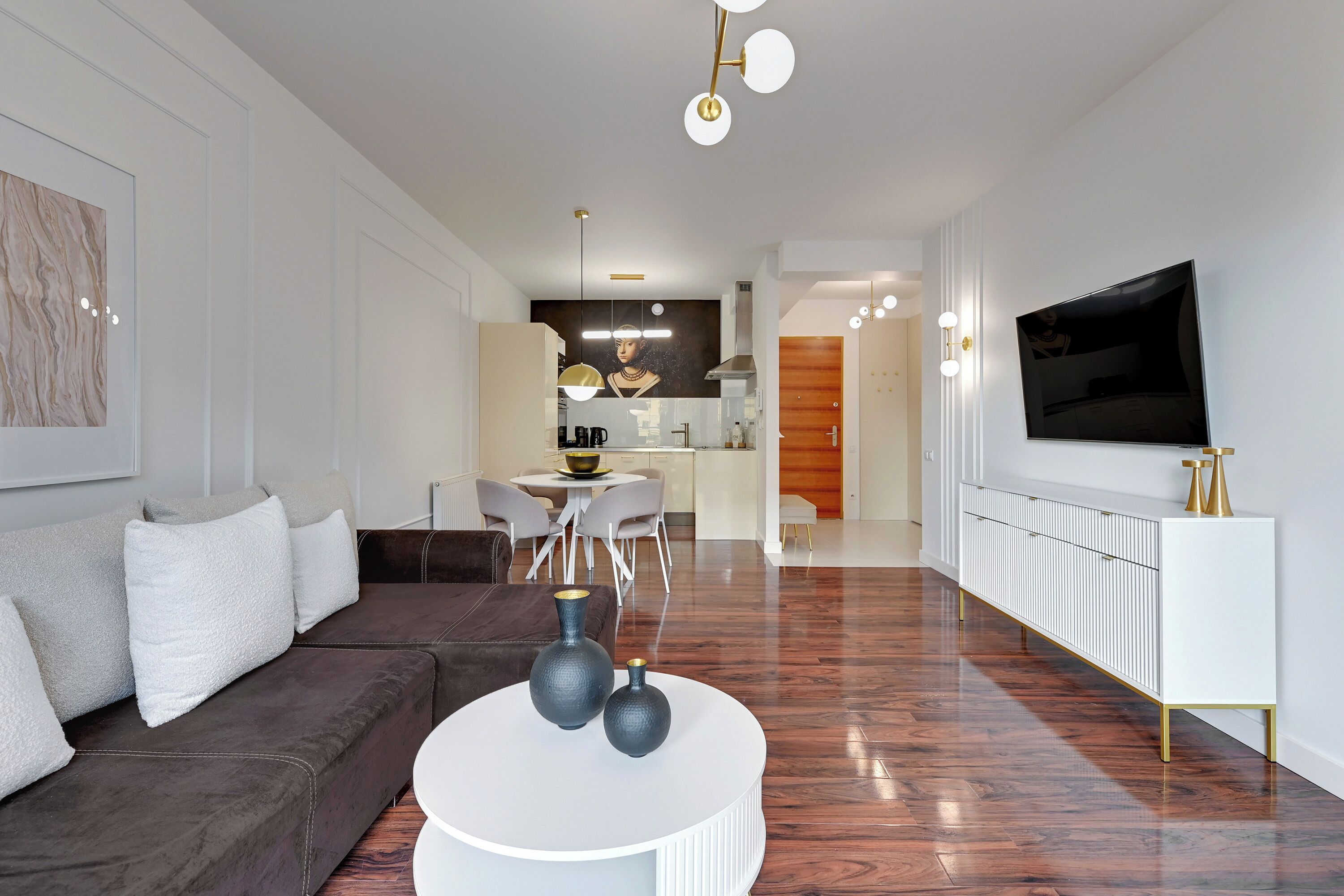 Ein modernes Wohnzimmer mit einem braunen Sofa, einem weißen Couchtisch und einem an der Wand befestigten Fernseher.
