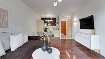 Ein modernes Wohnzimmer mit einem braunen Sofa, einem weißen Couchtisch und einem an der Wand befestigten Fernseher.