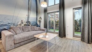 Een moderne woonkamer met een groot raam, een bank, een salontafel en een muurschildering van een zeilboot.