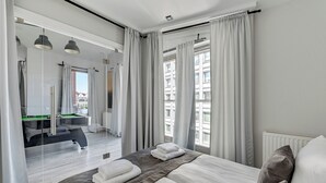 Een moderne hotelkamer met een groot bed, een bureau en uitzicht op een stadsbeeld.