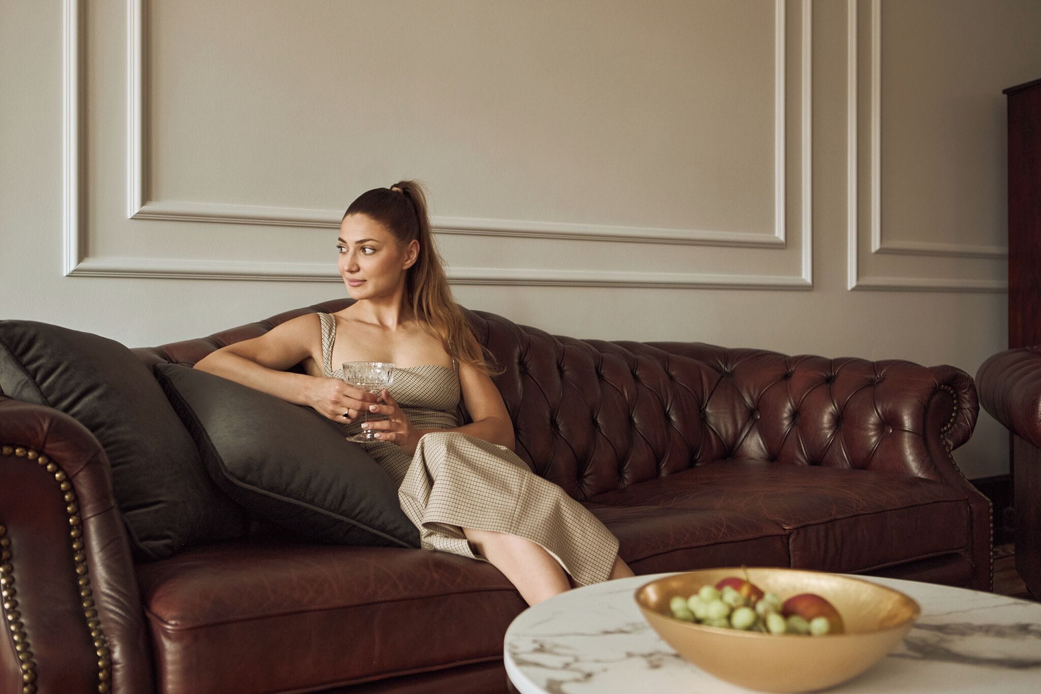 A person seated on a brown leather sofa with a marble table in front.