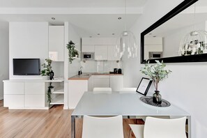 A modern kitchen with white cabinets, a microwave, and a hanging light fixture. - Waterlane Riverside SPA, Pool & Gym by Downtown Apartments (Gdansk)