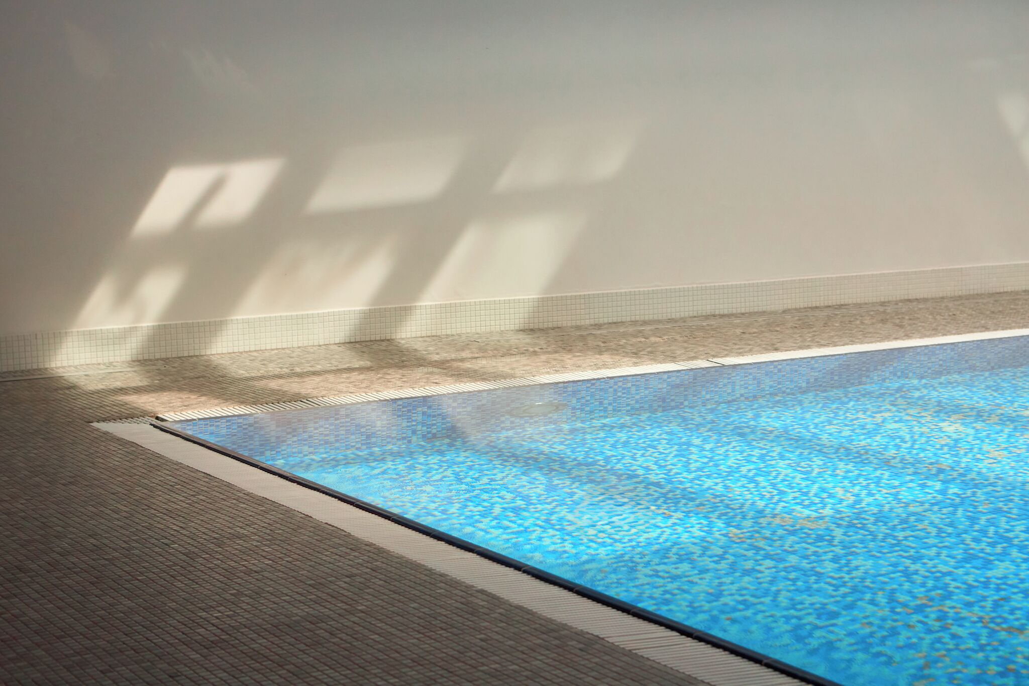 An indoor swimming pool with tiled walls and a tiled floor.