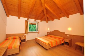 A room with two wooden beds, a window with curtains, and a bench. - Agritur Le Pergolette (Ville d'Anaunia)