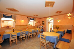 A dining area with multiple tables and chairs, wooden walls, and ceiling fans. - Agritur Le Pergolette (Ville d'Anaunia)
