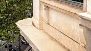 A stone balustrade with a window overlooking a cityscape.