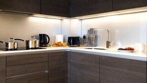 A modern kitchen with dark wood cabinets, a white countertop, and various appliances including a coffee maker, toaster, and kettle.