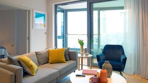 A modern living room with a grey sofa, a blue armchair, and a round coffee table with decorative items.