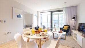 A modern living room with a dining area, featuring a sofa, a coffee table, and a television.