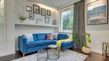 Una sala de estar moderna con un sofá azul, una mesa de centro y un amplio ventanal con cortinas.