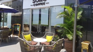 A café named SÔNG COFFEE with wicker chairs and a small table, a signboard, and a potted plant outside. - Enjoy Saigon Sunrise City (Ho Chi Minh City)