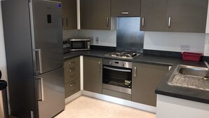 Eine moderne Küche mit Edelstahlgeräten, darunter ein Kühlschrank, eine Mikrowelle, ein Backofen und ein Gasherd.