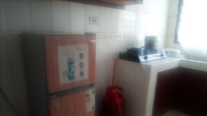 A kitchen with a refrigerator, a gas stove, and a red gas cylinder. - One World Apartments Bamburi (Mombasa)