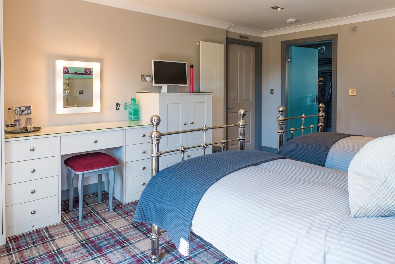 A bedroom with a bed, a desk with a chair, a mirror, and a wardrobe.