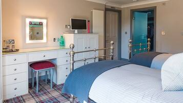 A bedroom with a bed, a desk with a chair, a mirror, and a wardrobe.