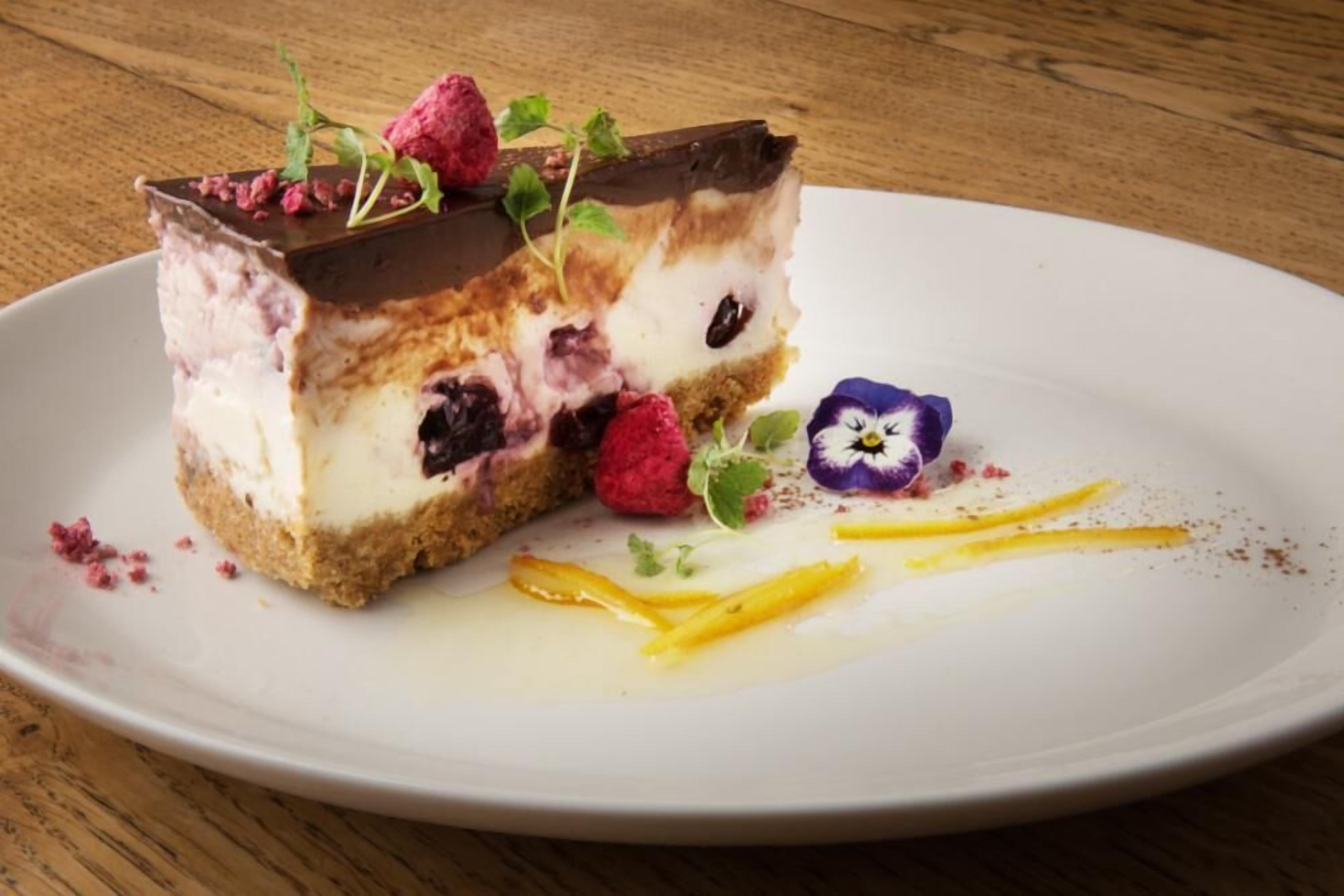 Una porció de postre en capes sobre un plat blanc, amb un fons de taula de fusta.