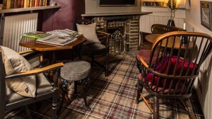 A cozy room with a fireplace, a television, and a table with books and magazines. - The Sawley Arms (Ripon)