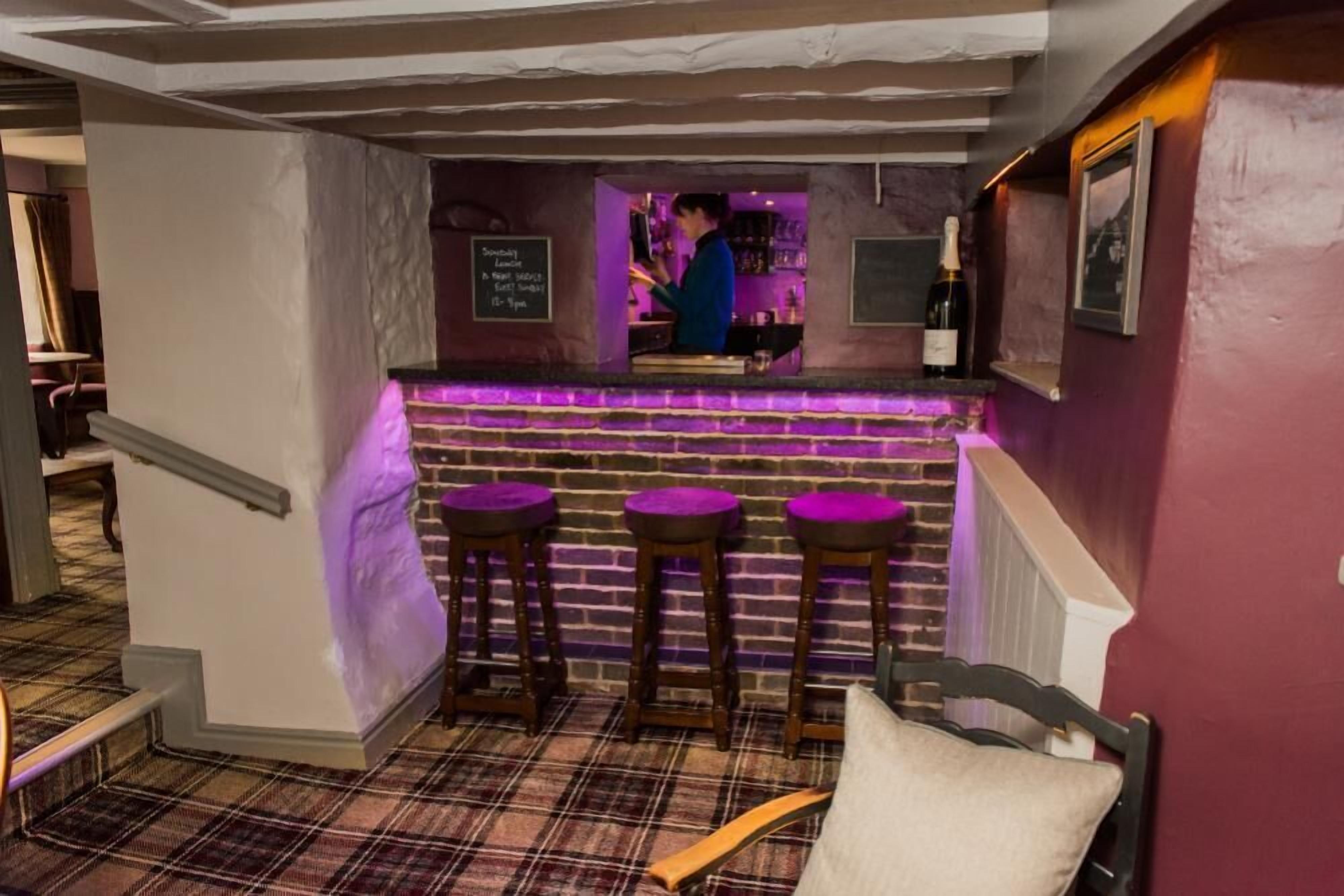 A bar area with a counter, stools, and a person behind the bar.