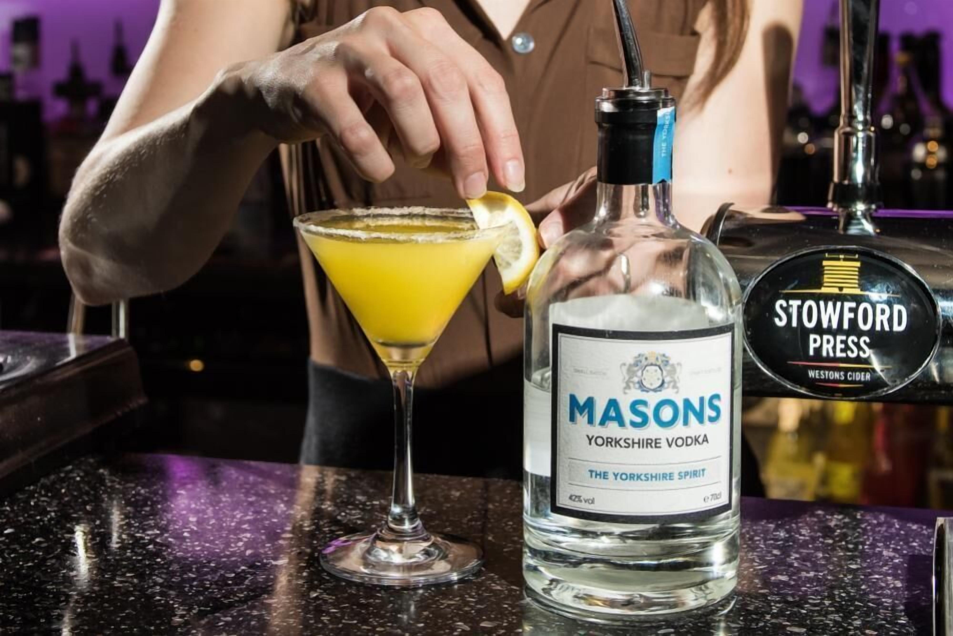 A bartender preparing a cocktail with a bottle of Yorkshire vodka and a glass.