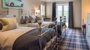 A bedroom with two beds, a plaid carpet, a window with curtains, and a wall with a car illustration. - The Sawley Arms (Ripon)