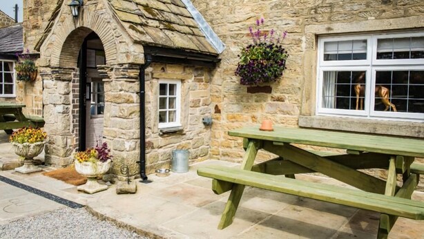 A stone building with a wooden door, windows, and a picnic table. - The Sawley Arms (Ripon)