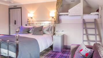 A hotel room with a bunk bed, a desk, a chair, and a plaid carpet.