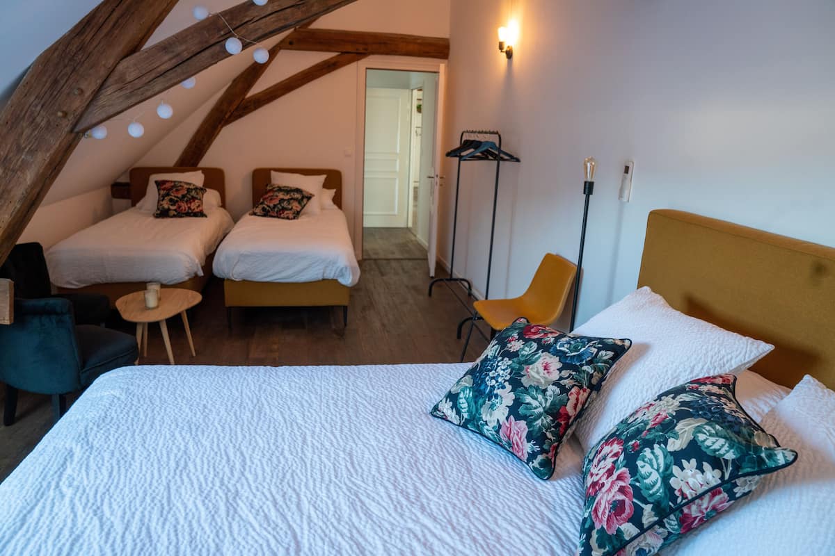 A bedroom with two beds, a wooden ceiling, a floor lamp, and a chair.