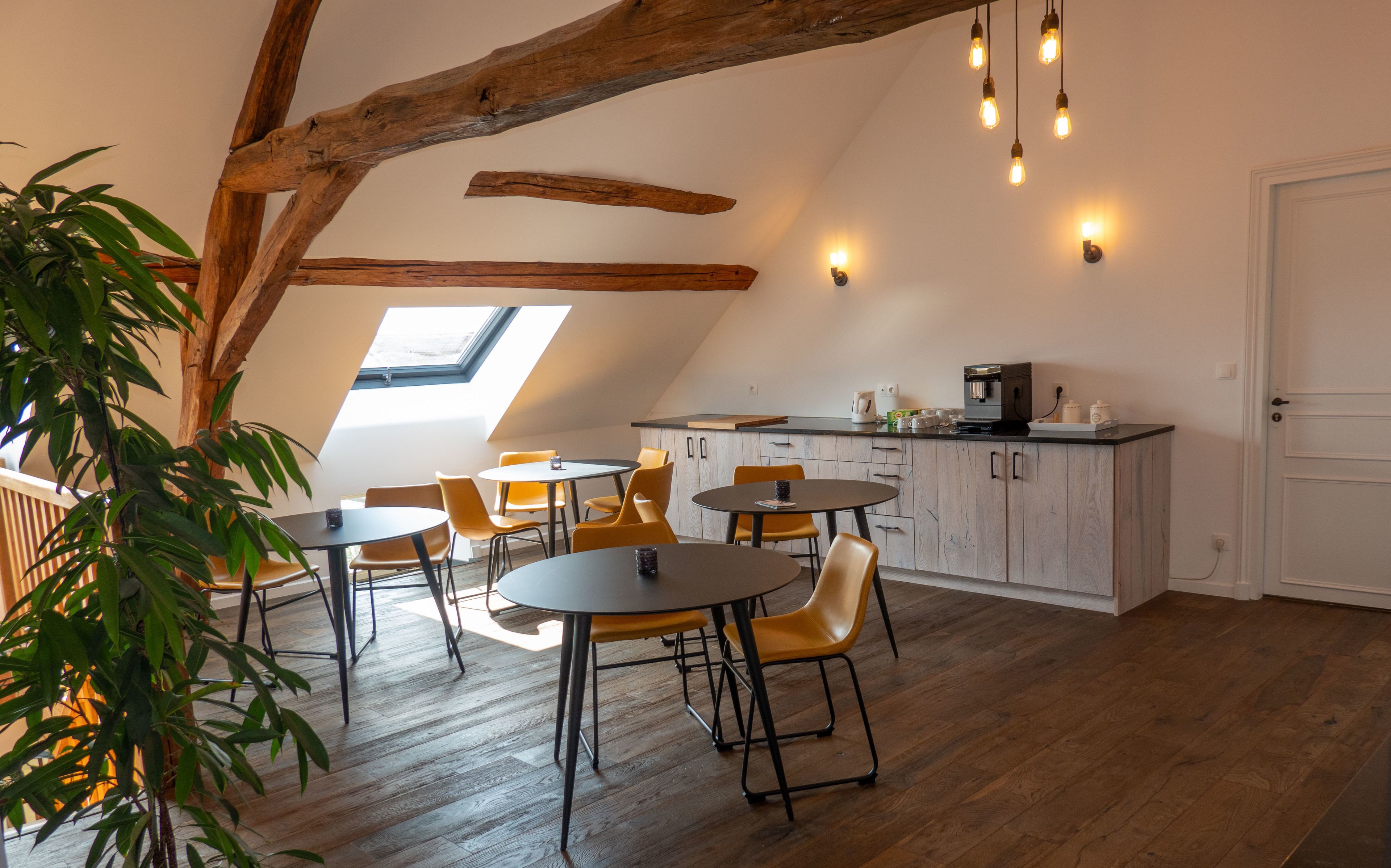 Un comedor acogedor con vigas de madera, tragaluces y una cocina con cafetera.