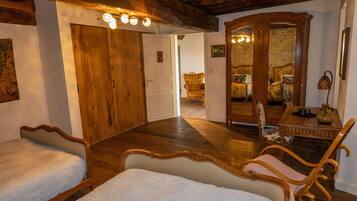 A room with two beds, wooden furniture, a mirror, and a wooden ceiling.