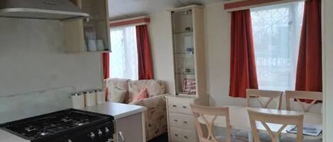 A compact kitchen with a stove, a small refrigerator, and a dining area with two chairs and a table.