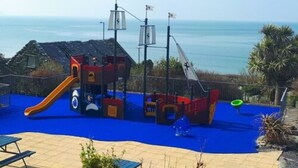 Ein Spielplatz mit Rutsche und Klettergerüsten in der Nähe von Gewässer.