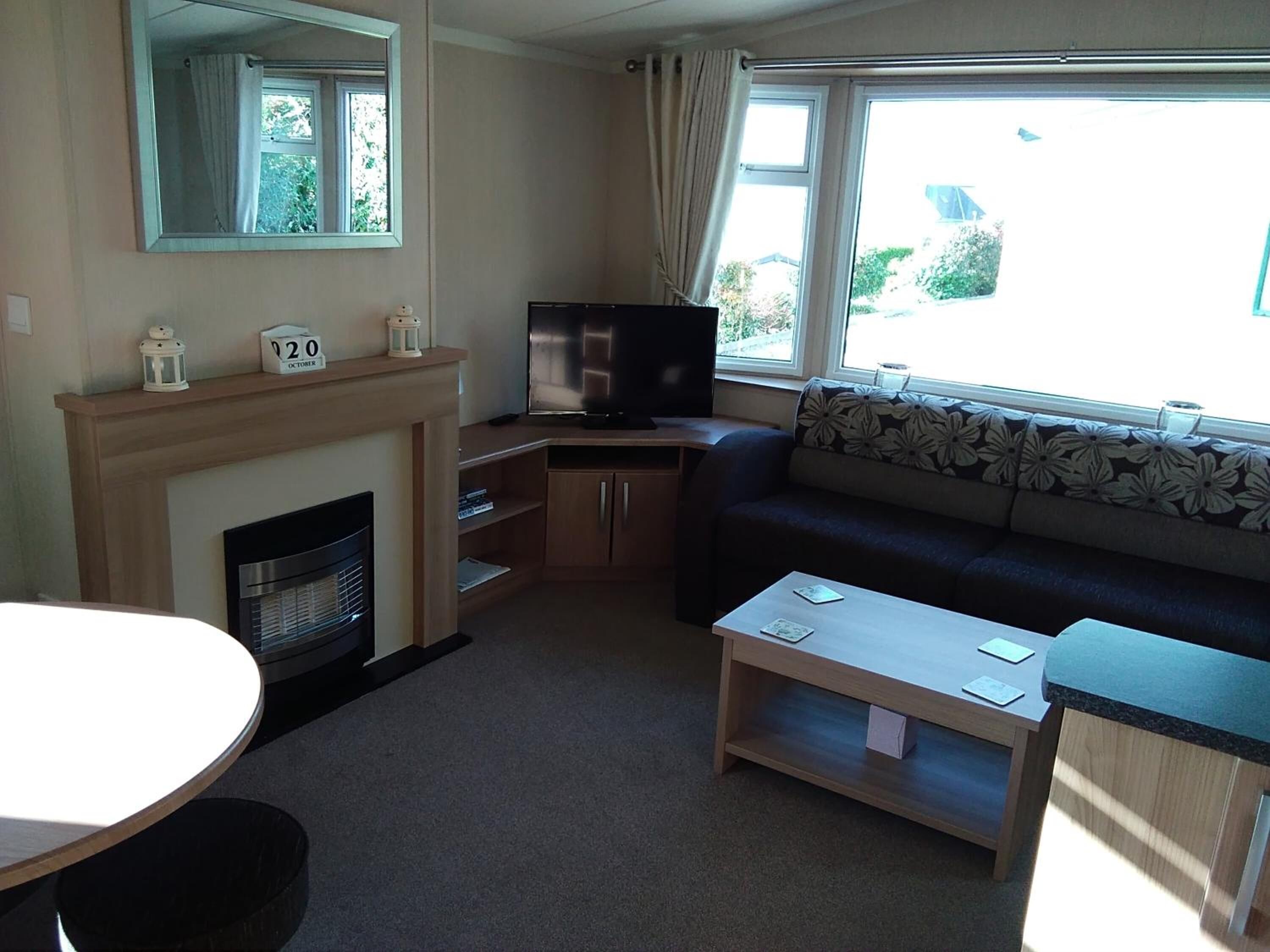 A compact living room with a fireplace, a television, a sofa, and a small table.